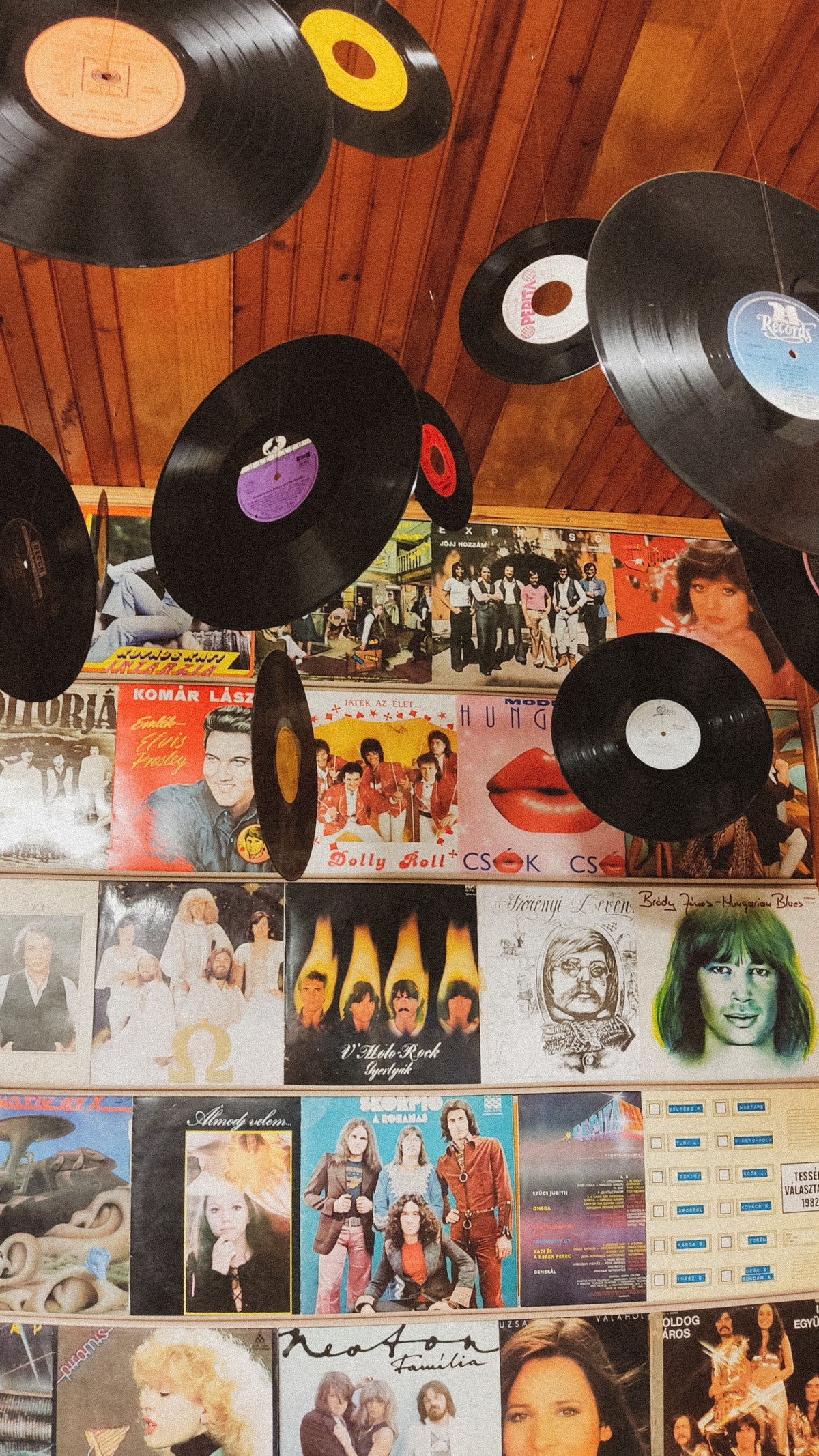 Collection of vinyl records and album covers on a wooden wall.